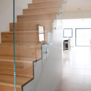 Staircase design by Rudi Tyrell with glass balustrade, with sleek storage underneath