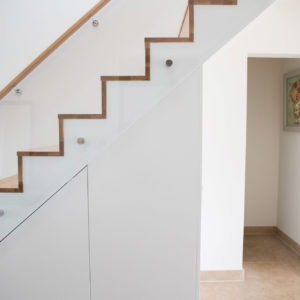 Staircase design by Rudi Tyrell with glass balustrade, with sleek storage underneath. The cabinets and storage are all from a local cabinet maker, Peter Kemp.