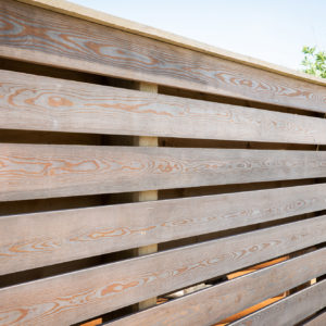Open larch fencing matches the cladding on the garden room