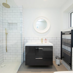 Dark grey towel rail and vanity units are set off my the dark grey tile grout