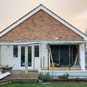 We propped up the existing roof and build the new walls underneath to keep most of the rain out.