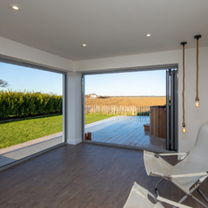 Double bi-fold doors open out onto a composite decking and hot tub