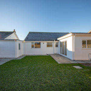 The view of the rear of the property showing the new kitchen extension to the right, and the door to the left to the garage/utility