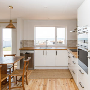 The kitchen is a blend of old and new. Newly sanded floor, new handles, existing cabinets, new worktops, new lighting, existing table/chairs. And sea view - timeless!